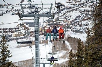 A group of skiers ride up the ski lift. 