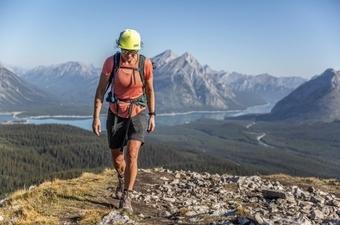 Awoman walks along the ridgeline in a mountain range wearing a pair of REI Sahara Convertible pants